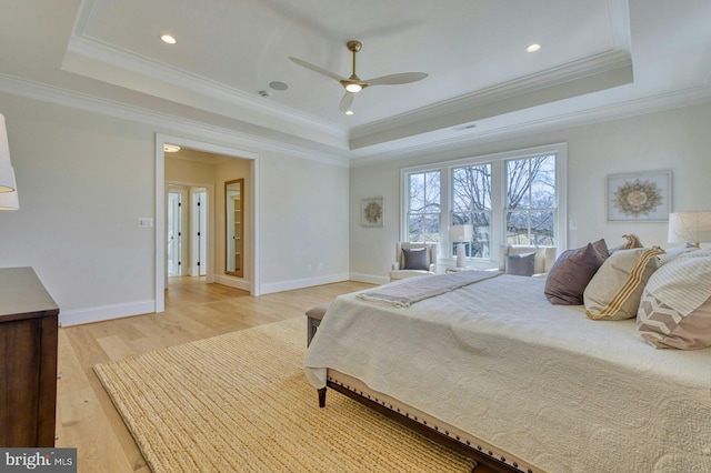 bedroom featuring light wood-type flooring, a tray ceiling, and baseboards