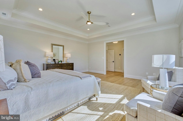 bedroom with baseboards, ornamental molding, a raised ceiling, and light wood-style floors