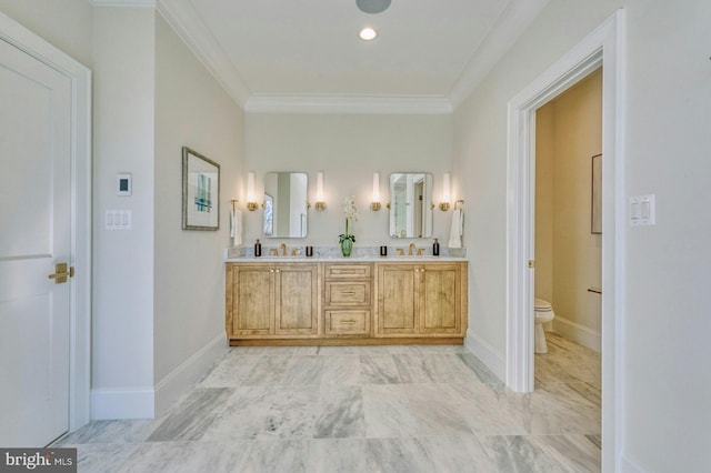 bathroom with crown molding, double vanity, toilet, a sink, and baseboards