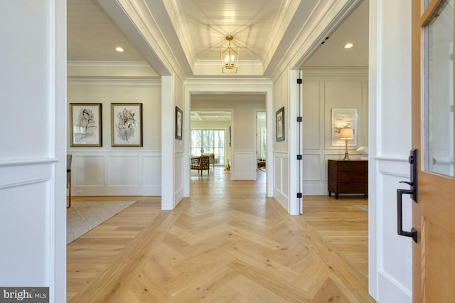 entrance foyer with an inviting chandelier, ornamental molding, and a decorative wall