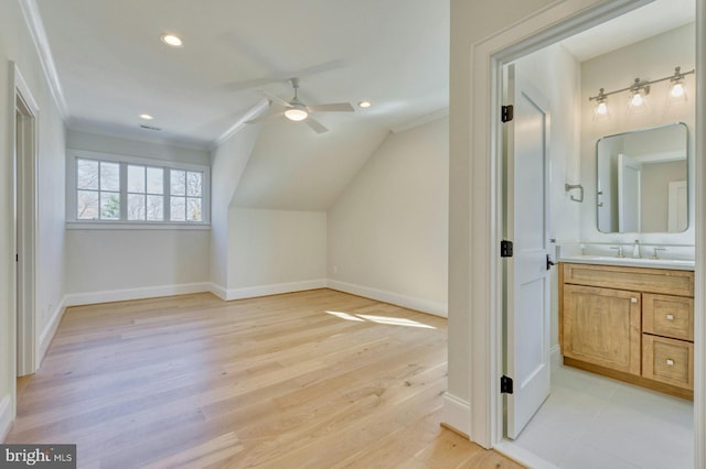 additional living space featuring a ceiling fan, light wood-type flooring, a sink, and baseboards