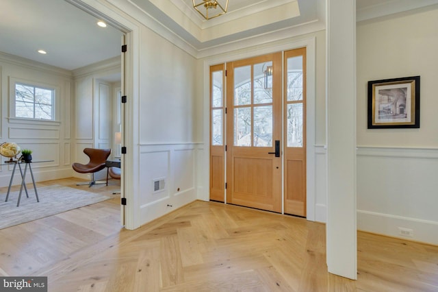 foyer entrance with visible vents, ornamental molding, a decorative wall, and recessed lighting