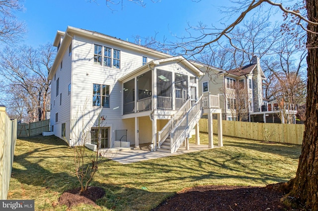 back of property with a lawn, a patio, a sunroom, a fenced backyard, and stairs