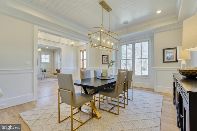 dining area featuring light wood finished floors, wood ceiling, a notable chandelier, and a wainscoted wall