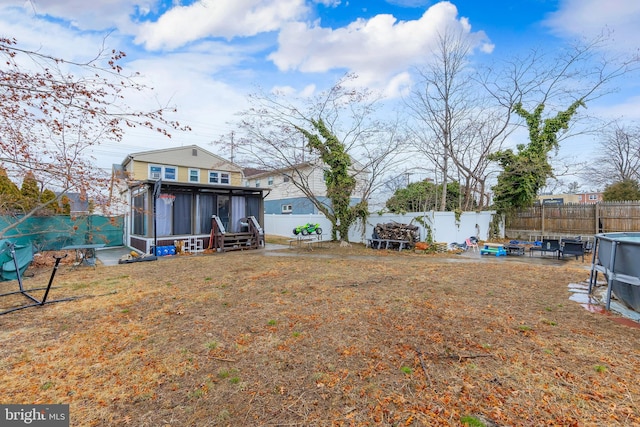 view of yard with a sunroom, a fenced backyard, a fenced in pool, and a patio