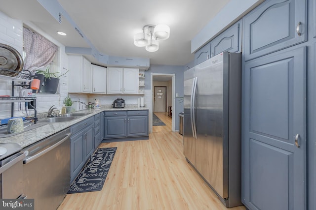 kitchen with tasteful backsplash, appliances with stainless steel finishes, light wood-style floors, open shelves, and a sink