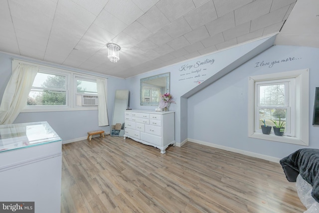 bedroom with cooling unit, light wood-style flooring, and baseboards