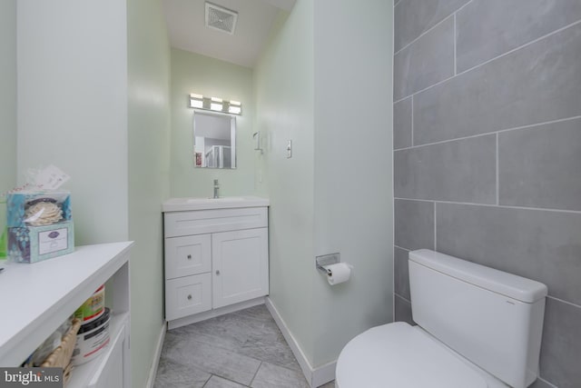 bathroom featuring toilet, baseboards, visible vents, and vanity