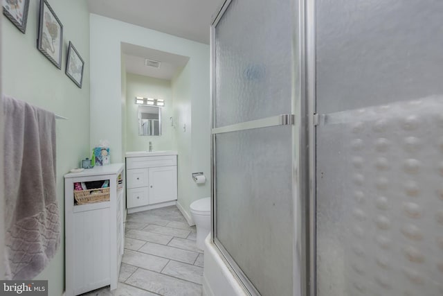 bathroom featuring visible vents, toilet, vanity, and a shower with shower door