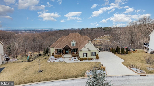 view of front of house featuring a front lawn, a wooded view, and concrete driveway