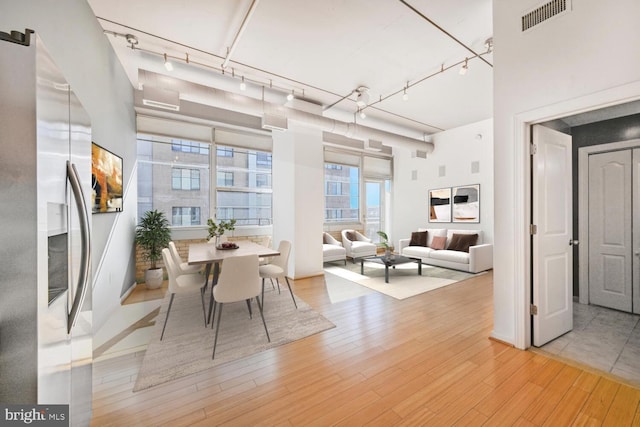 dining space with light wood-type flooring, rail lighting, and visible vents