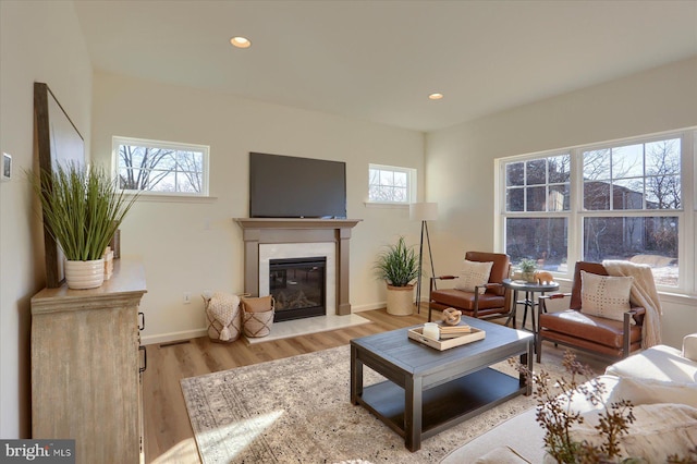 living area with baseboards, light wood finished floors, a fireplace, and recessed lighting