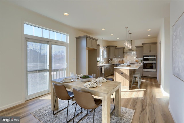 dining room with light wood-type flooring, baseboards, and recessed lighting