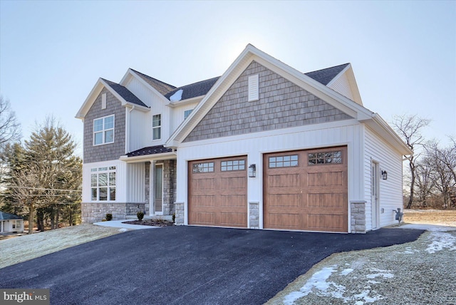 view of front of house featuring aphalt driveway, stone siding, and a garage