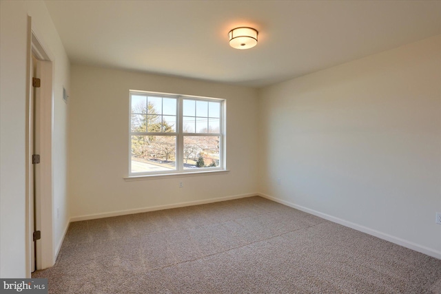 carpeted spare room featuring baseboards