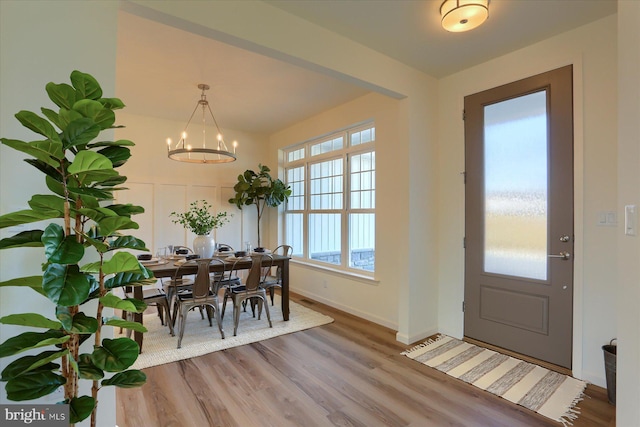 dining space featuring baseboards, wood finished floors, and a notable chandelier