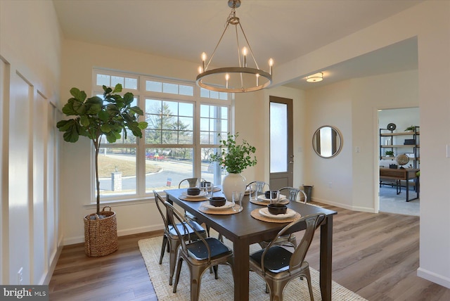 dining space with baseboards, wood finished floors, and an inviting chandelier