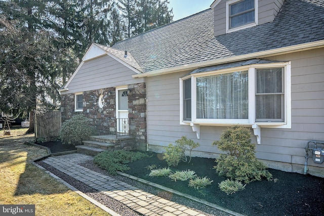 view of front facade featuring stone siding and roof with shingles