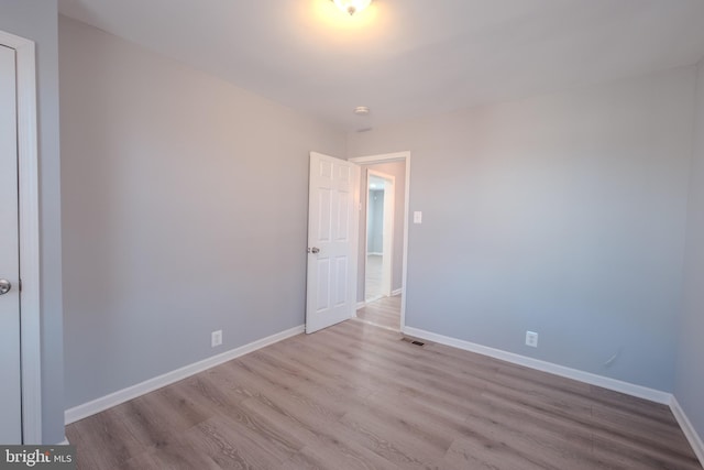 empty room with light wood-style floors, visible vents, and baseboards