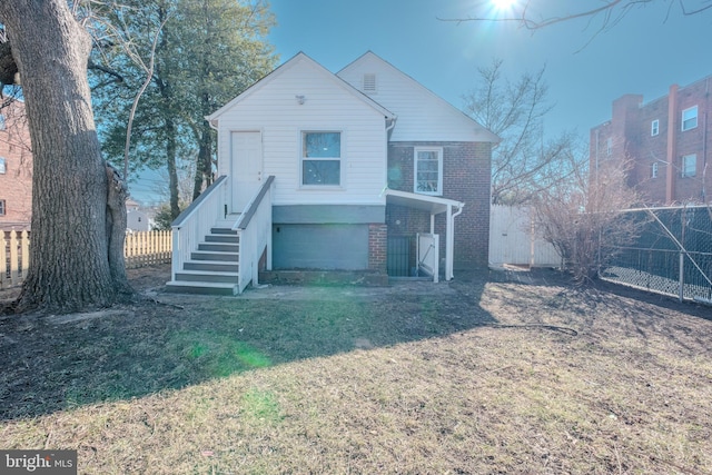 view of front of property with a front yard, brick siding, and fence