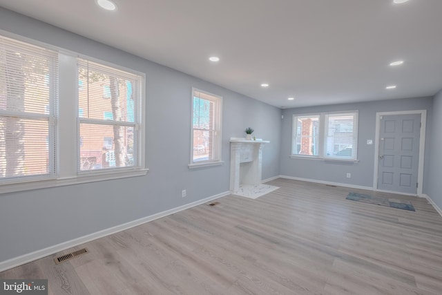 unfurnished living room featuring recessed lighting, a high end fireplace, visible vents, baseboards, and light wood finished floors