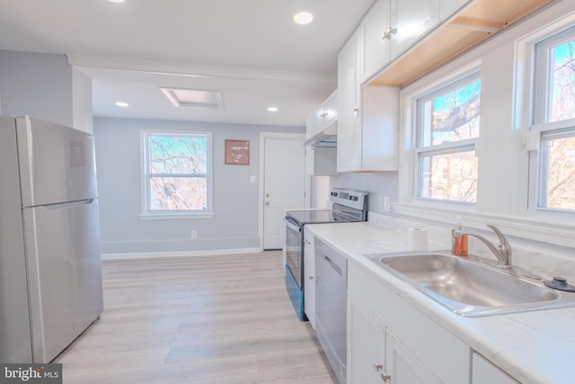 kitchen with white cabinets, a healthy amount of sunlight, stainless steel appliances, and a sink