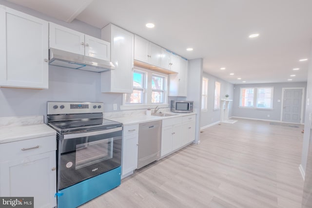 kitchen with white cabinets, under cabinet range hood, stainless steel appliances, and open floor plan