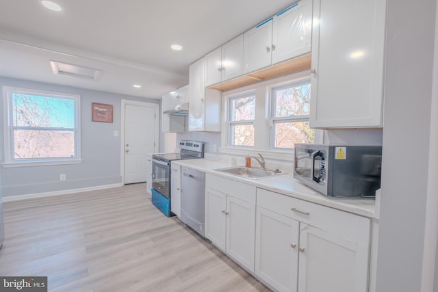 kitchen with appliances with stainless steel finishes, a sink, white cabinetry, and a healthy amount of sunlight