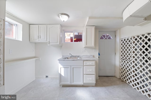 kitchen featuring white cabinets, plenty of natural light, light countertops, and a sink