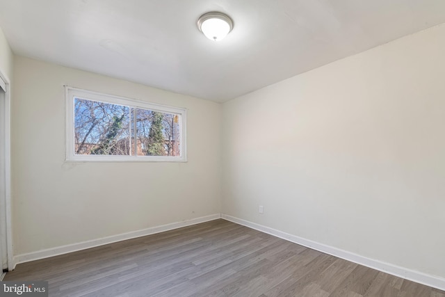 spare room with baseboards and wood finished floors