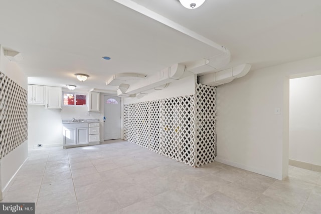 empty room featuring light tile patterned flooring, a sink, and baseboards