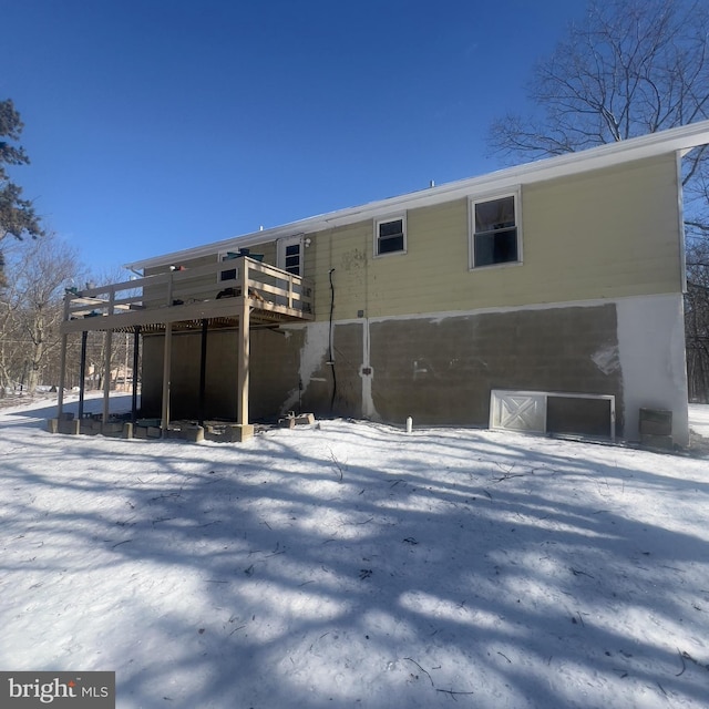 snow covered back of property with a deck