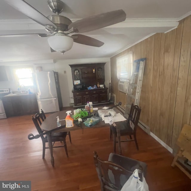 dining area with wooden walls, wood finished floors, baseboard heating, and ornamental molding