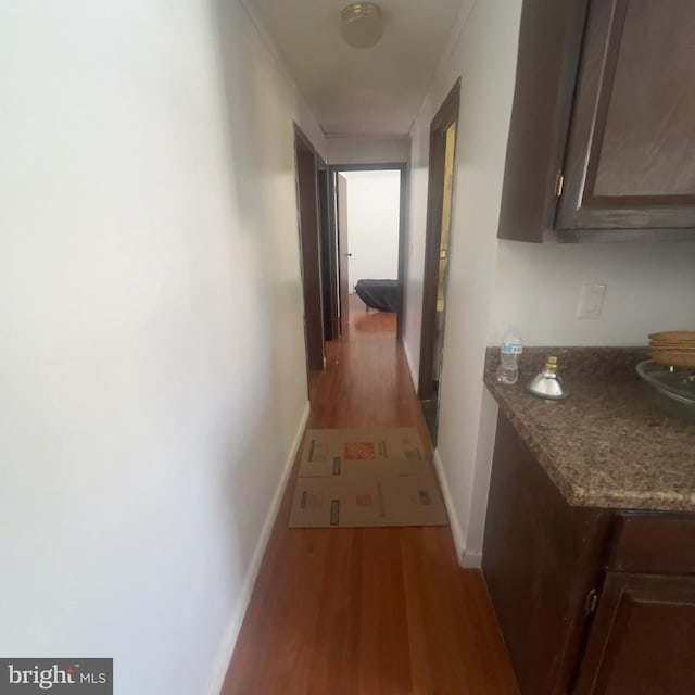 hall featuring light wood-style flooring and baseboards