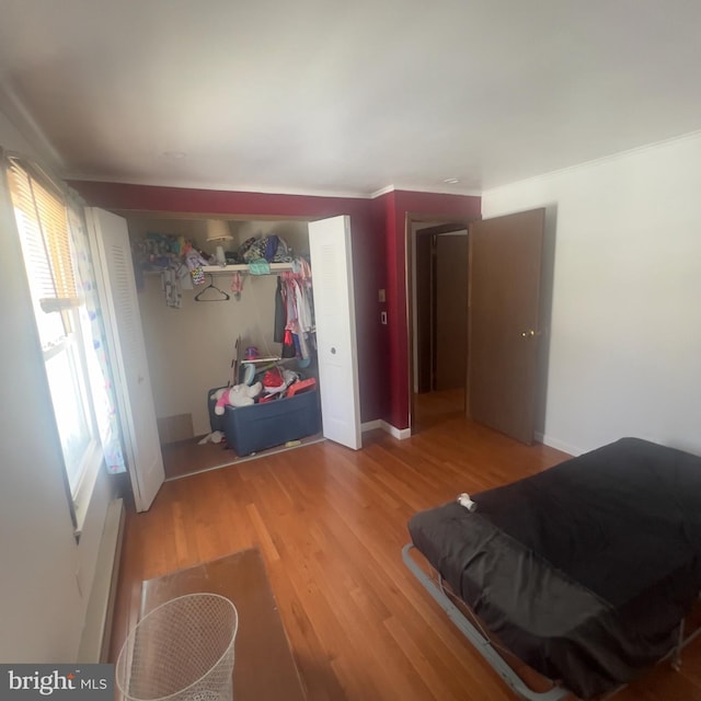 bedroom featuring a closet, light wood-style flooring, baseboards, and multiple windows