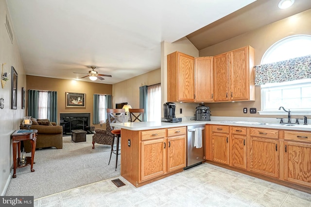 kitchen featuring a peninsula, a fireplace, a sink, open floor plan, and light countertops