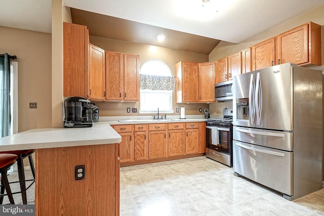 kitchen featuring a breakfast bar, a peninsula, vaulted ceiling, stainless steel appliances, and light countertops