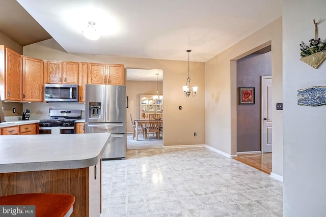 kitchen with decorative light fixtures, stainless steel appliances, light countertops, an inviting chandelier, and baseboards