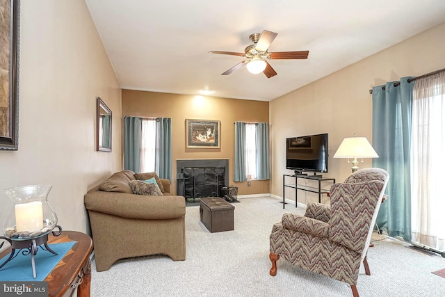 living room featuring ceiling fan, carpet floors, a fireplace, and baseboards