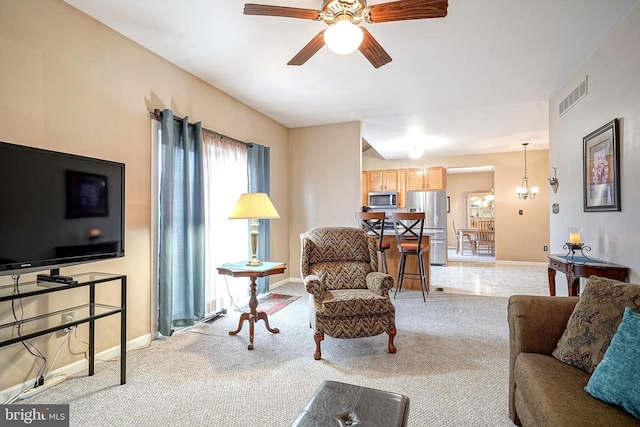 living room featuring baseboards, visible vents, a ceiling fan, and light colored carpet