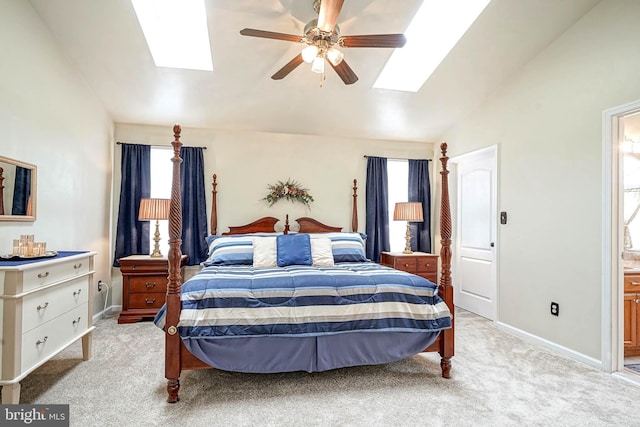 carpeted bedroom featuring lofted ceiling with skylight, a ceiling fan, baseboards, and ensuite bathroom