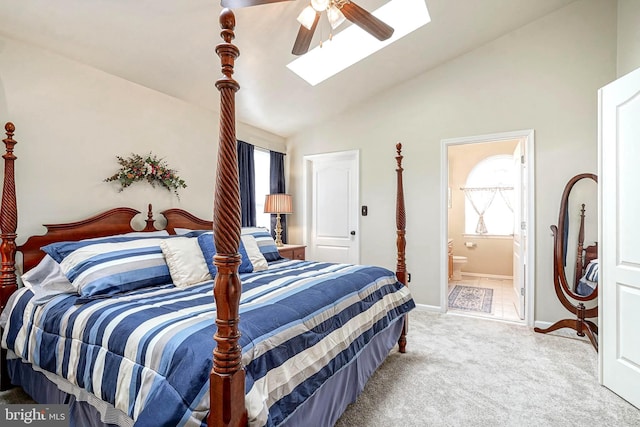 carpeted bedroom with lofted ceiling with skylight, baseboards, a ceiling fan, and ensuite bathroom