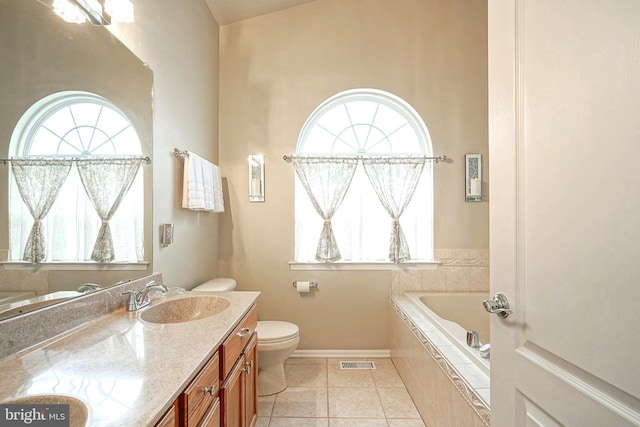 bathroom featuring tile patterned flooring, toilet, vanity, visible vents, and tiled tub