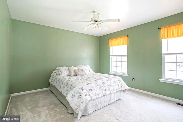 carpeted bedroom featuring a ceiling fan, visible vents, and baseboards