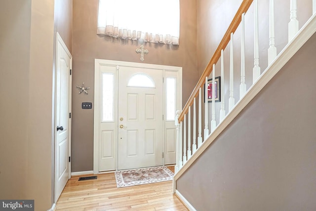 entryway with a towering ceiling, visible vents, stairway, and hardwood / wood-style floors