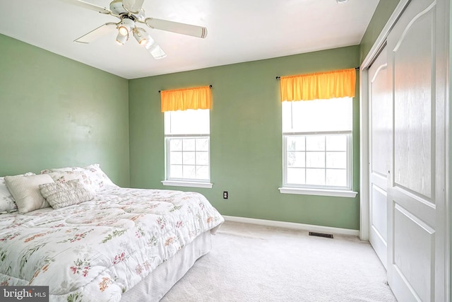 carpeted bedroom featuring a ceiling fan, a closet, visible vents, and baseboards