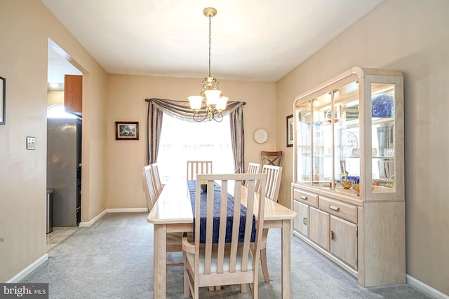 dining space with a notable chandelier, baseboards, and light colored carpet