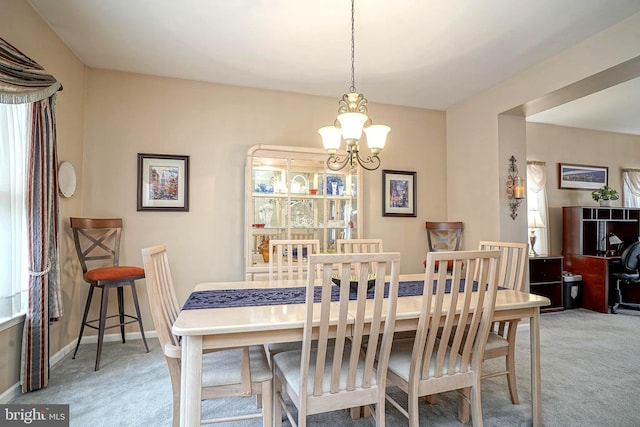 carpeted dining area with baseboards and a notable chandelier