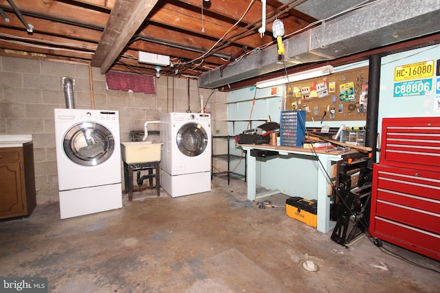 unfinished basement featuring a workshop area, a sink, concrete block wall, and washer and dryer