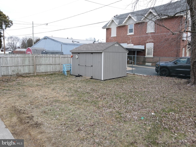 view of yard with a fenced backyard, a storage unit, and an outbuilding